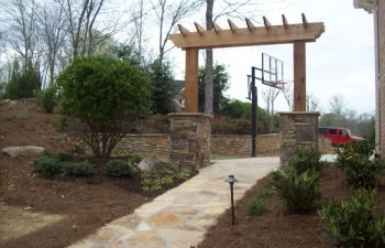 wooden arbor with stone bases and garden stone walkway by Mobile Joe's Landscaping