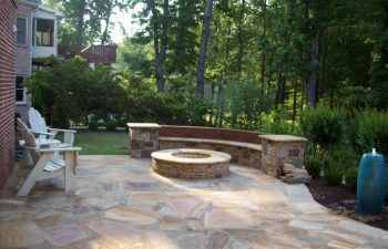 flagstone patio with a fire pit and stone bench