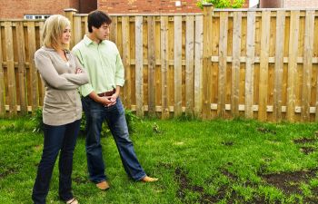 Concerned couple looking at rusts on their lawn.